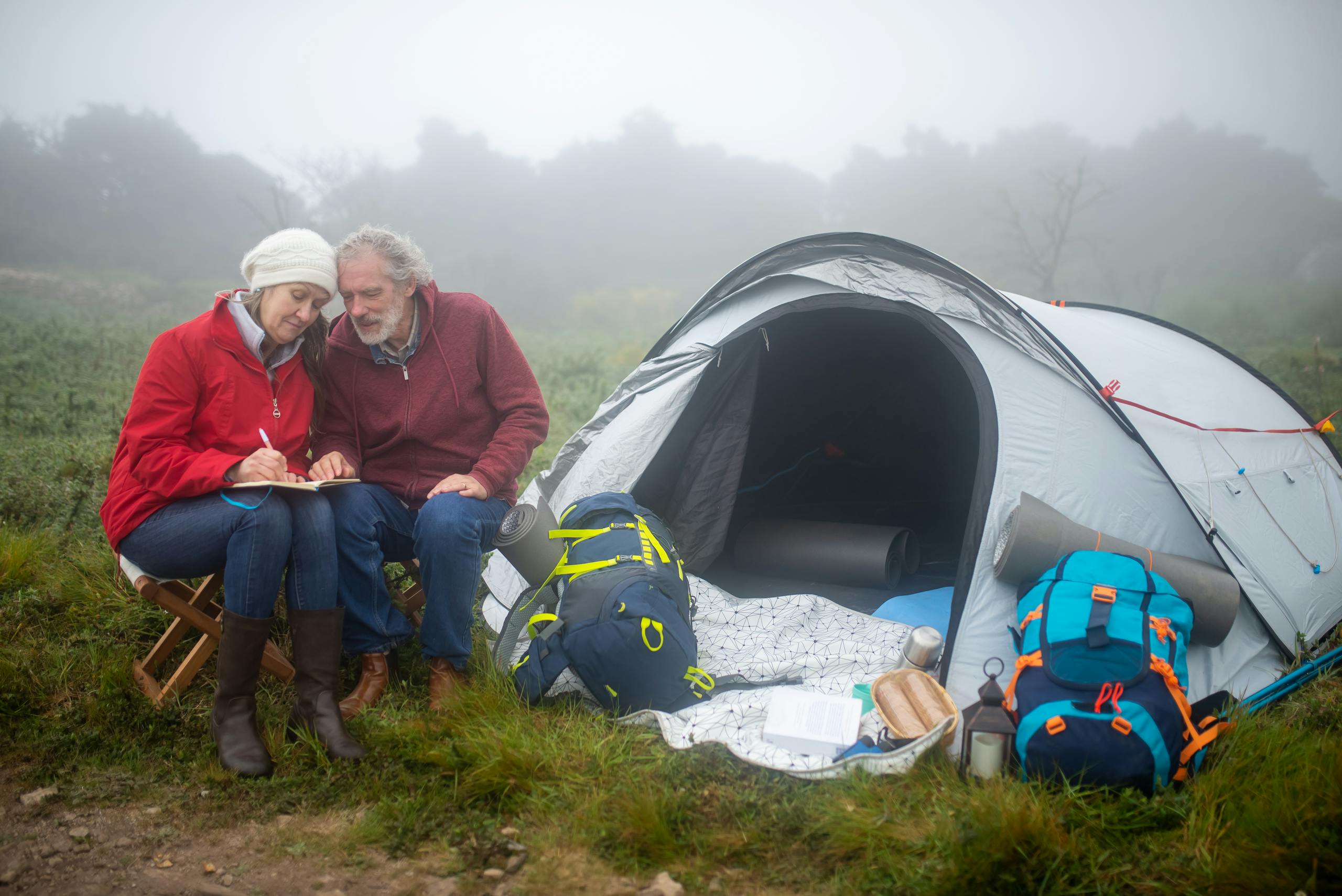 An Elderly Couple Writing on a Notebook while Camping